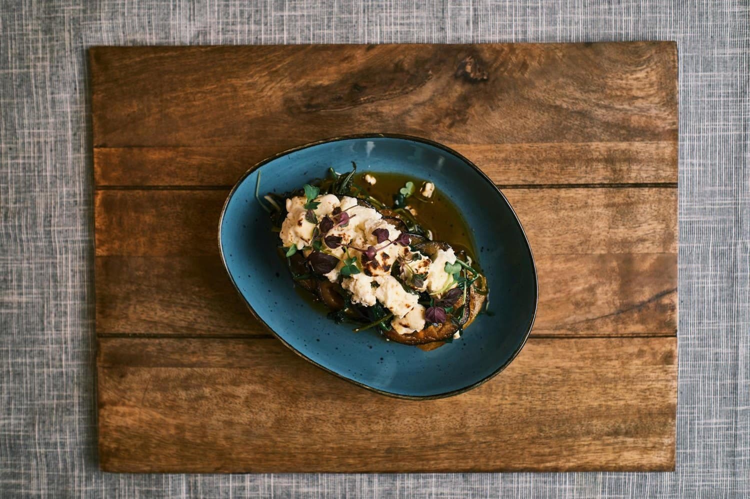 Angerichteter Teller: gegrillte Aubergine mit Burrata und Kräutern